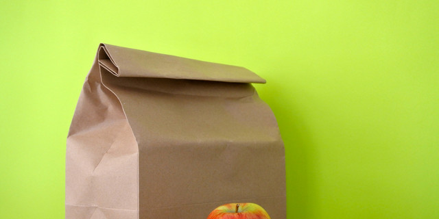 Lunch packed in a brown paper bag with red apple