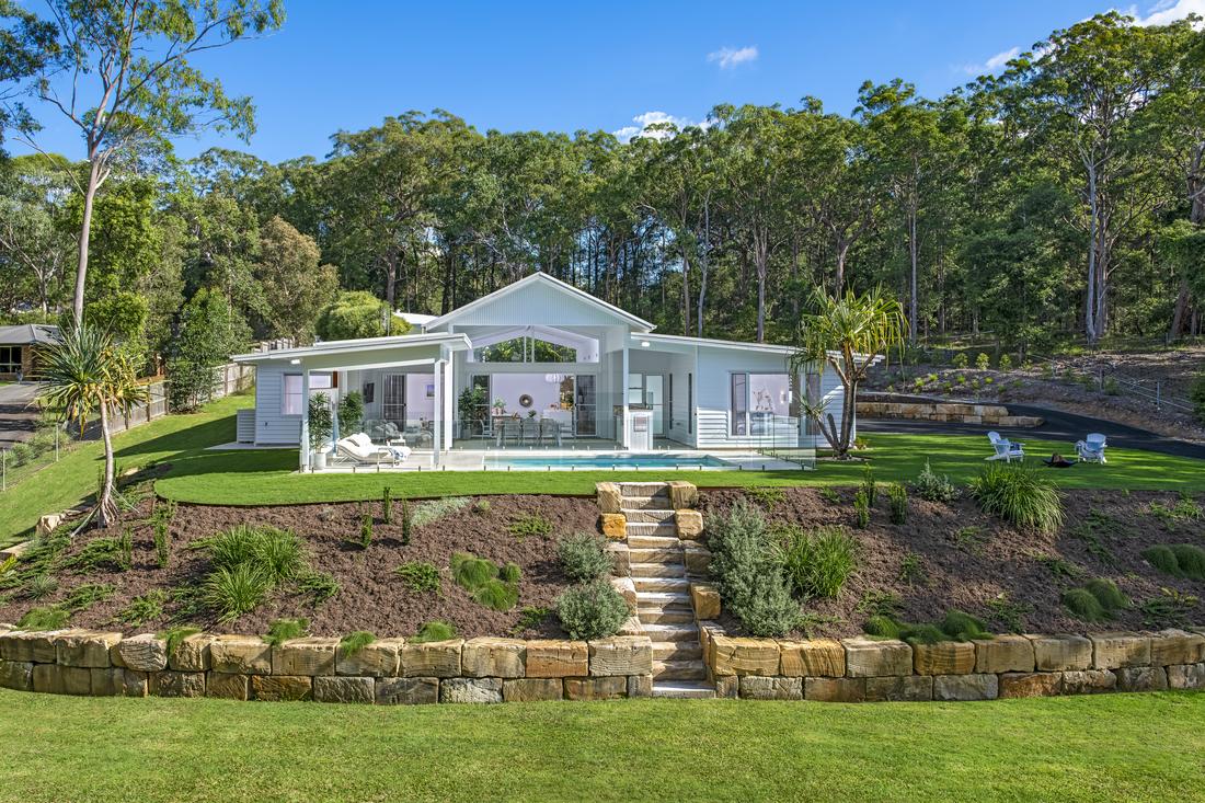 A white house with a pool surrounded by acreage.