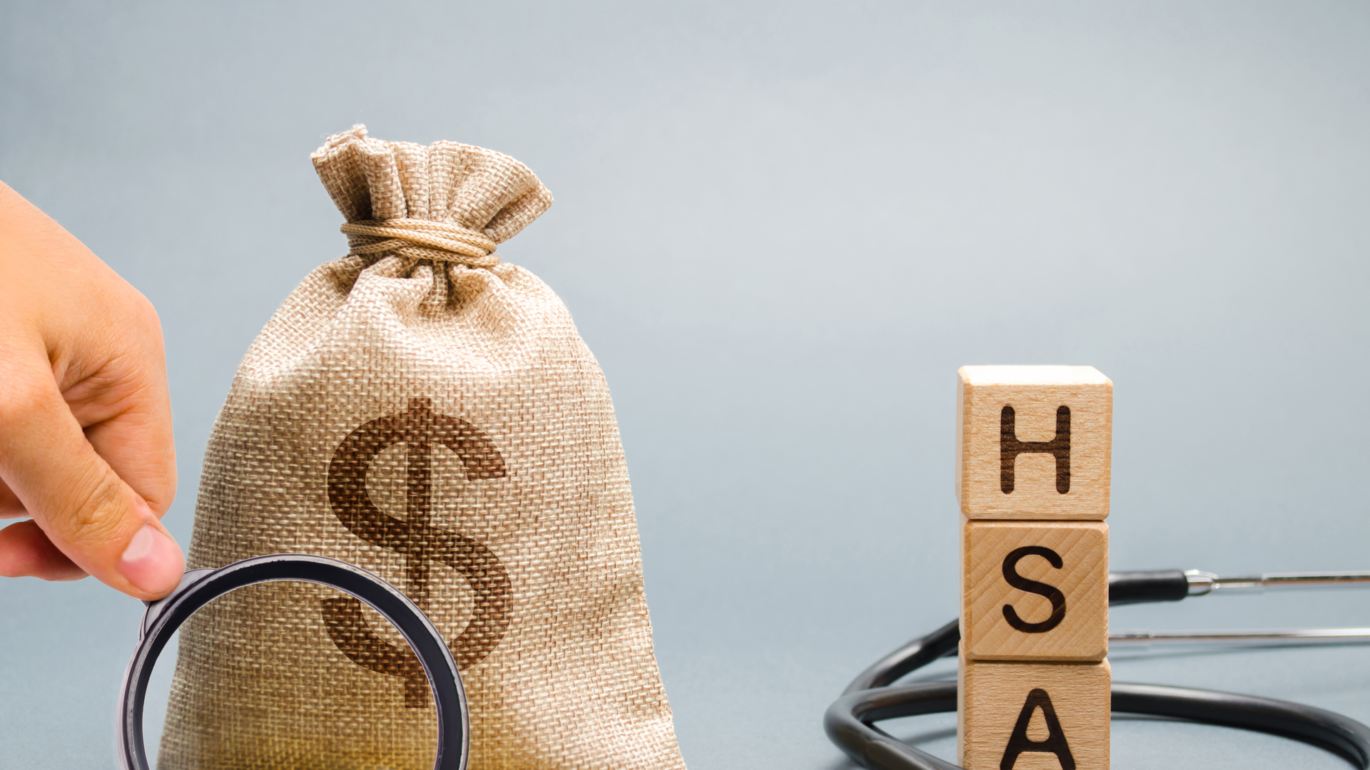 Wooden blocks with the word HSA and money bag with stethoscope. Health savings account. Health care. Health insurance. Investments. Tax-free medical expenses. Coins and dollar sign