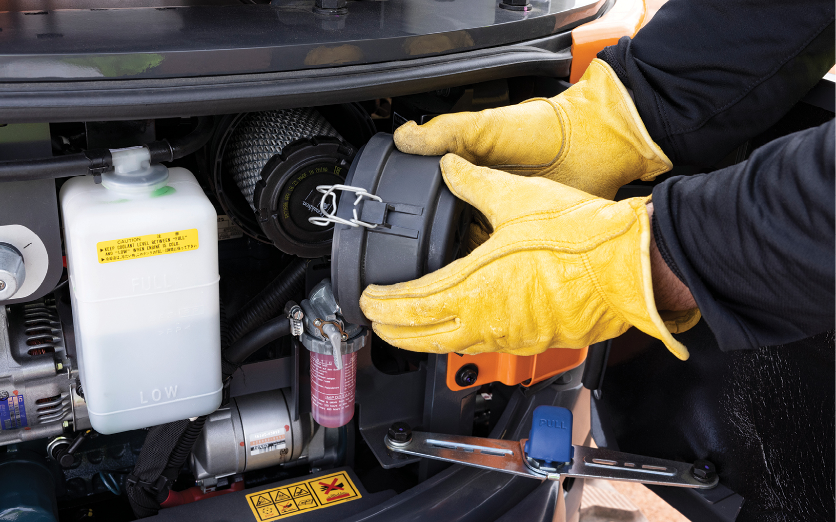 An operator secures the cover on a mini excavator filter canister.