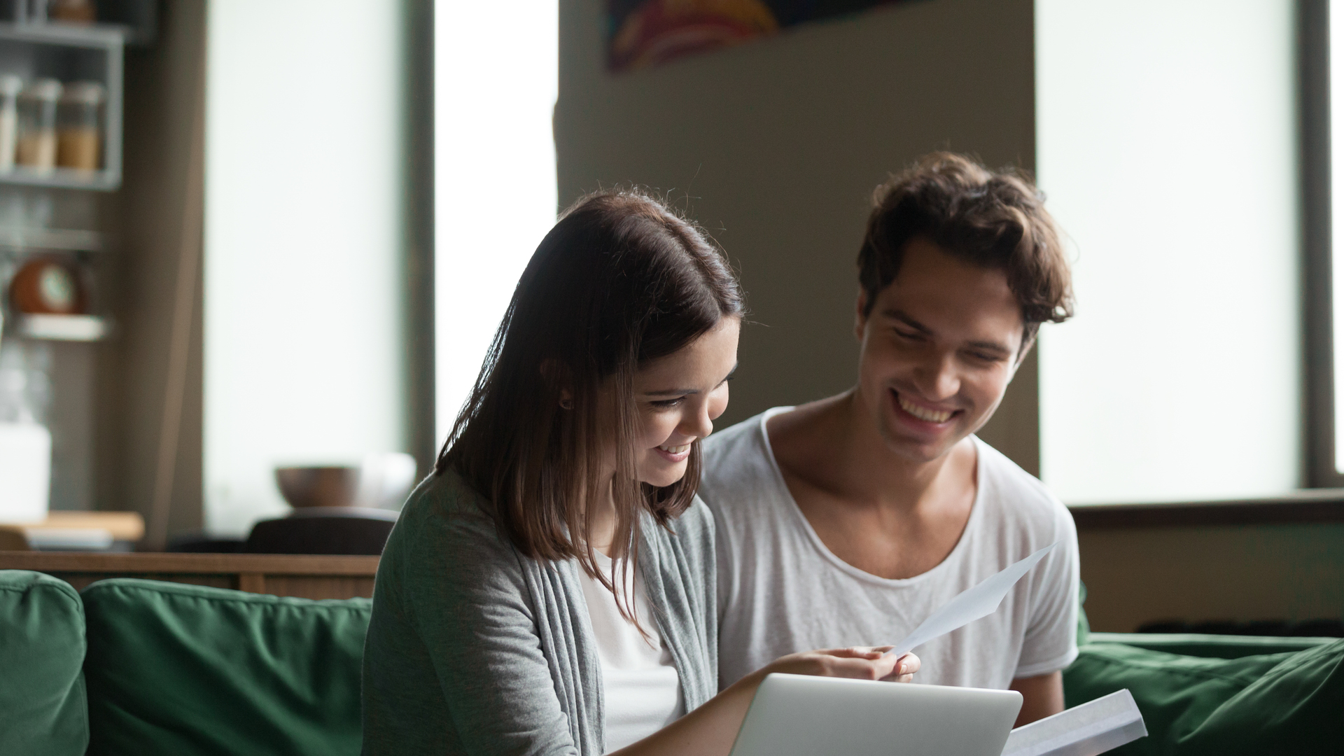 Happy couple with bills and laptop at home