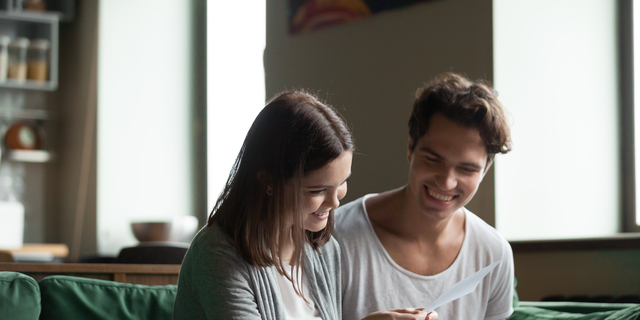 Happy couple with bills and laptop at home