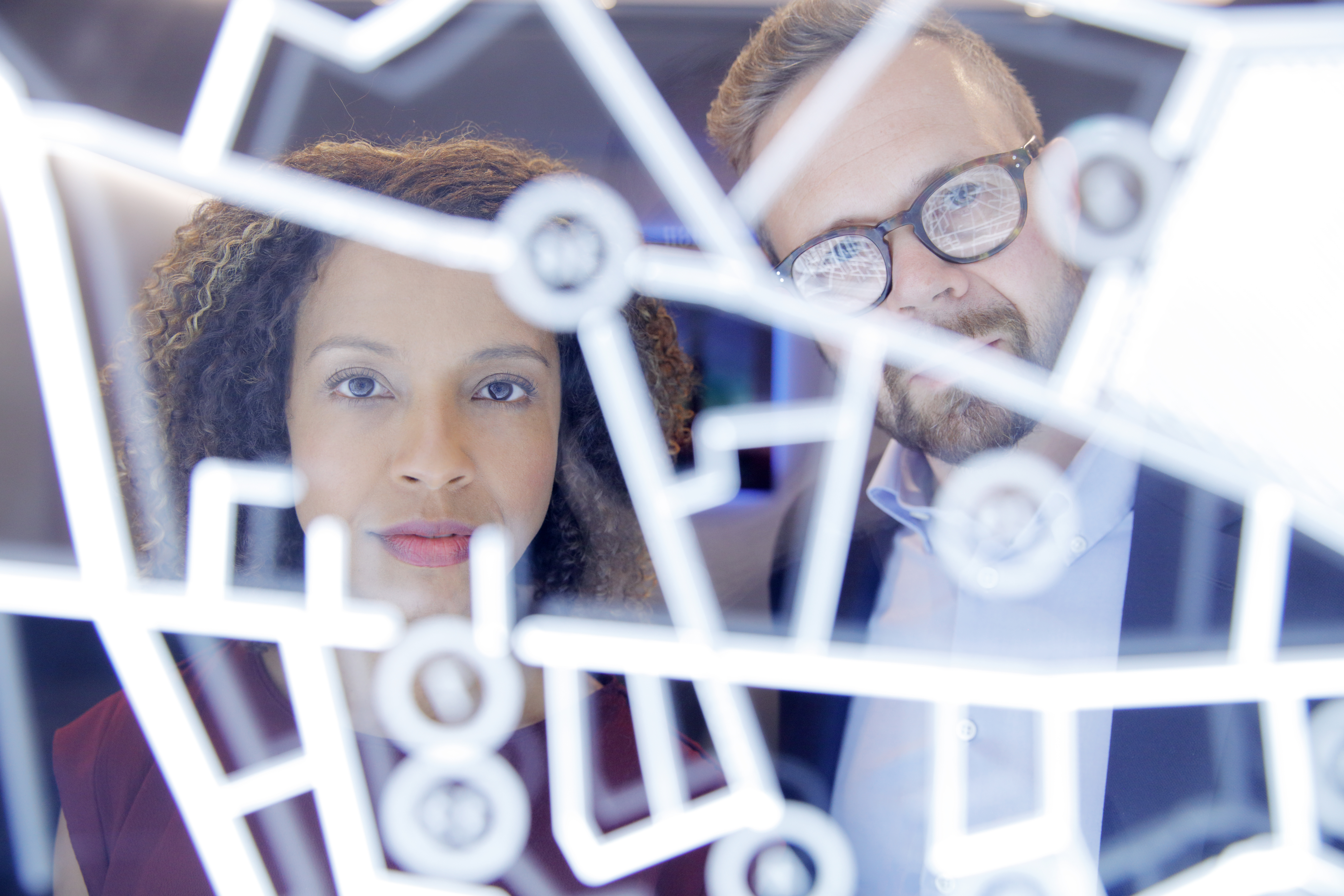 A man and a woman stare at a cybersecurity solutions grid on a display.