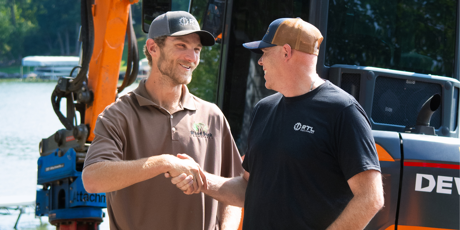 Business owner and DEVELON dealer shake hands in front of a crawler excavator.