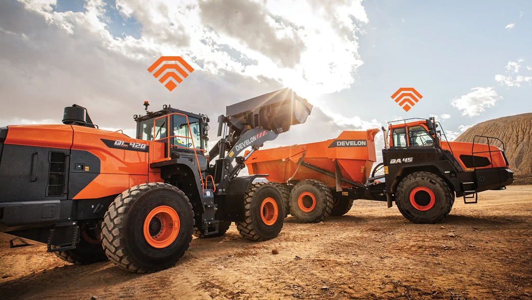 A DEVELON wheel loader preparing to dump material into a DEVELON articulated dump truck with Wi-Fi signals over each machine.