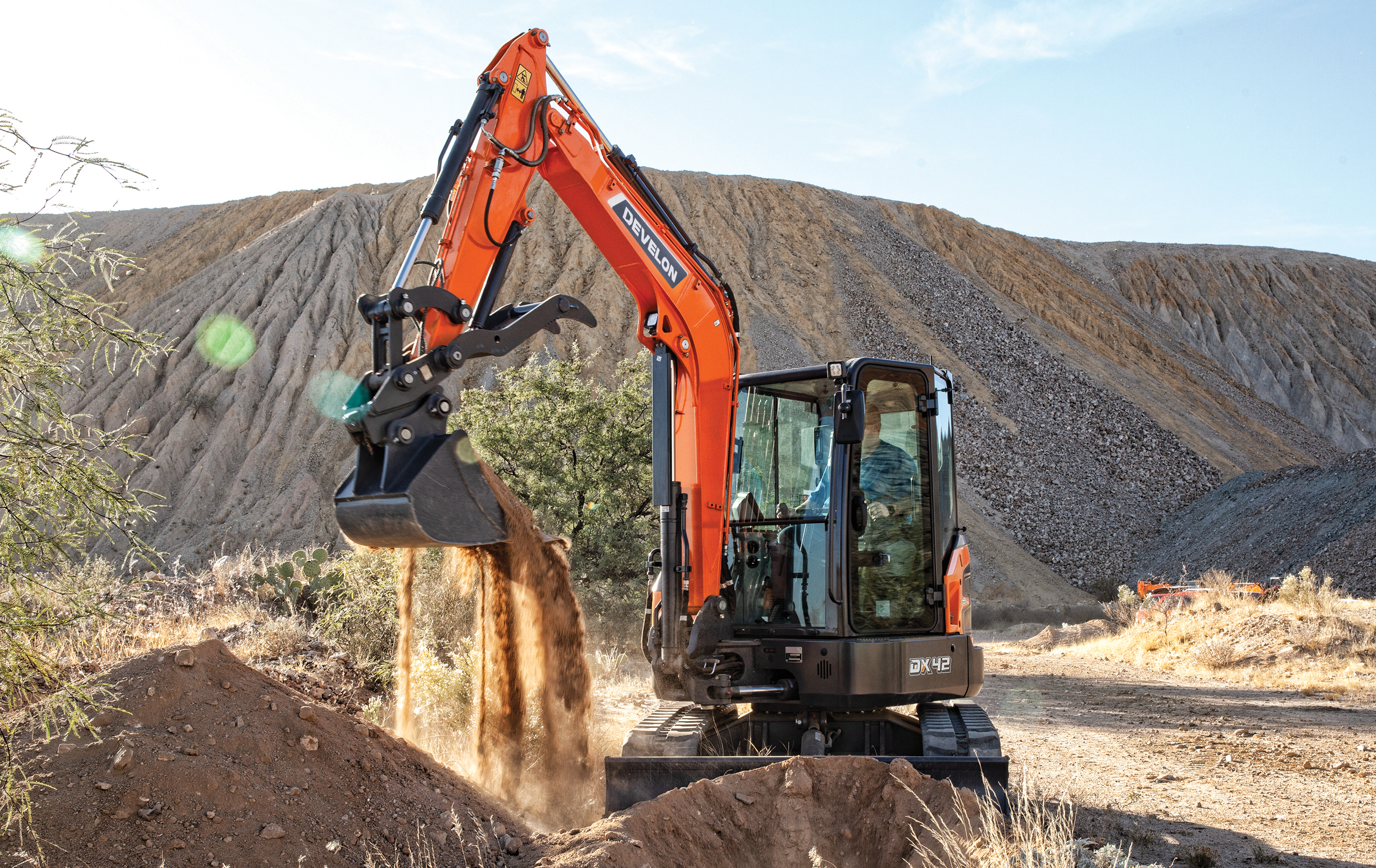 The DEVELON DX42-7 mini excavator scooping dirt.