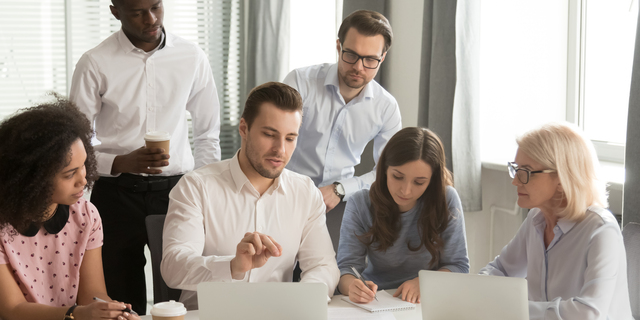 Company employees listening boss sitting at desk in boardroom