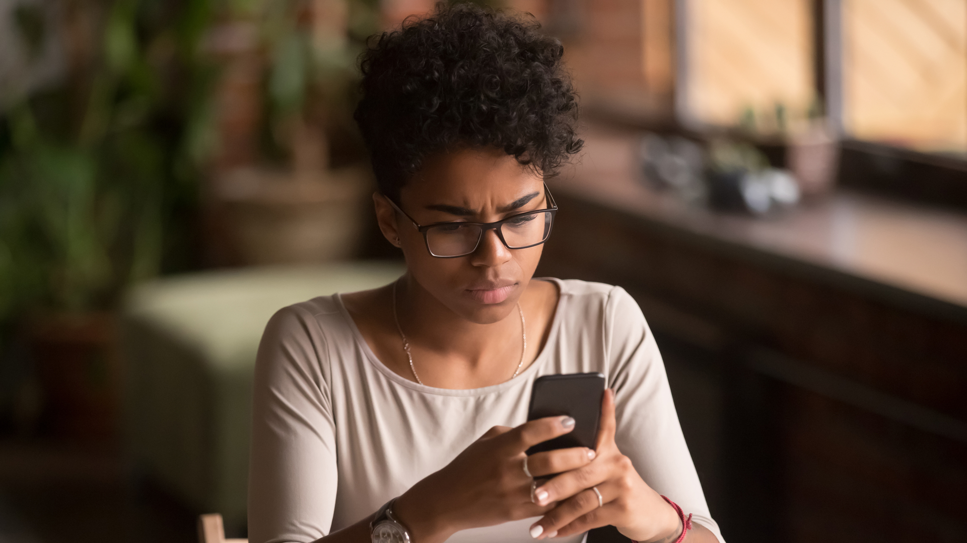 Upset confused african woman holding cellphone having problem with phone