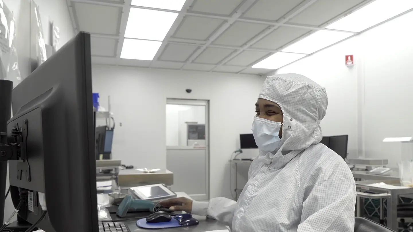 Woman in PPE working on computer in clean lab