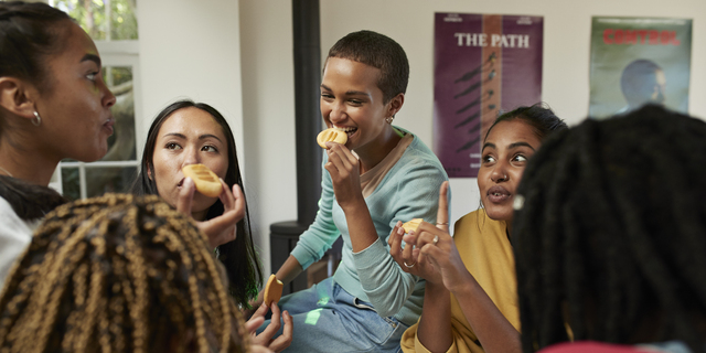 Friends talking while enjoying cookies at home