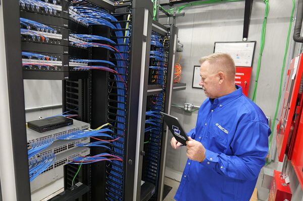 BICSI certified technician inspecting structured cabling and server rack hardware with a tablet