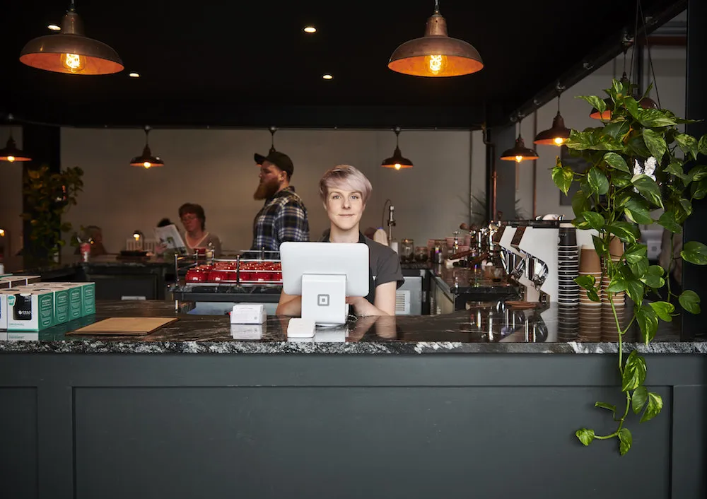 barista behind bar with Square Stand