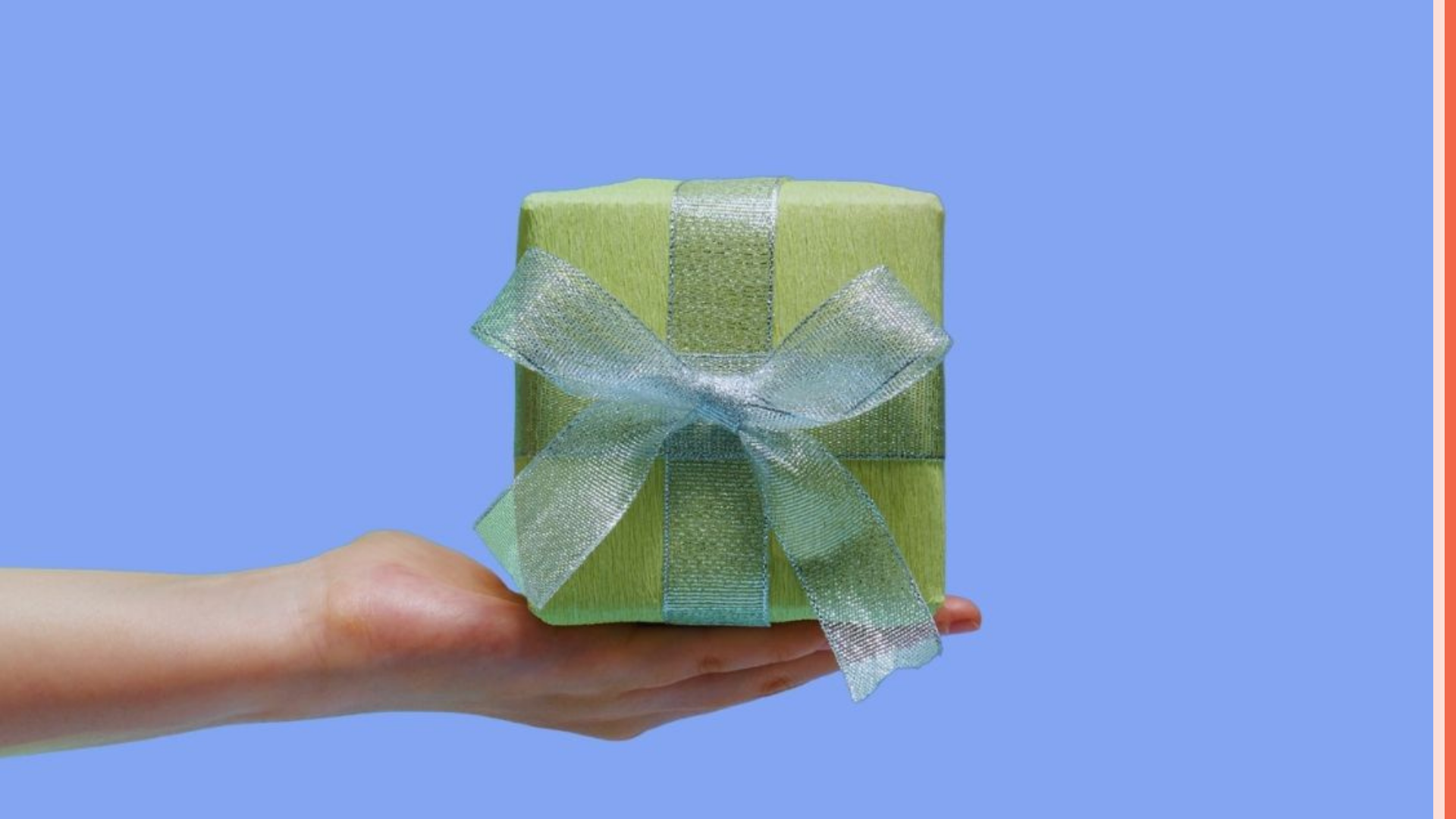 image of a hand holding a present wrapped in green paper and a green ribbon.