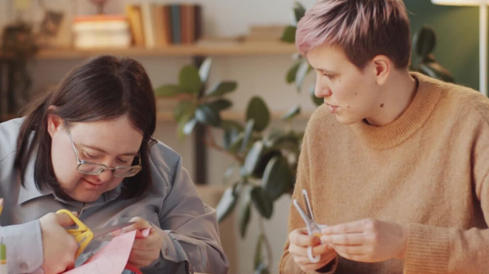 Photo of a support worker crafting with a girl