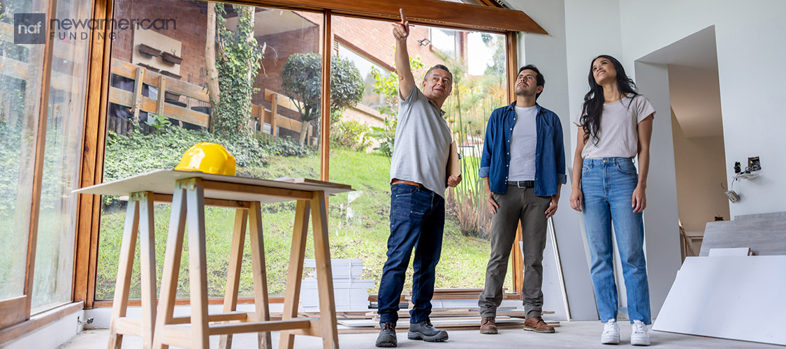 A home builder talks excitedly to a couple in their home