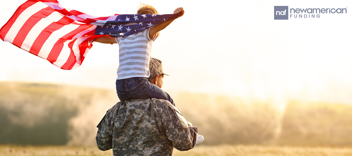 military father with his son on his shoulder holding an American flag