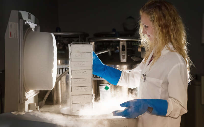 Scientist pulling research specimens from biorepository freezer