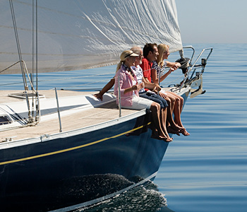 Prijatelji na jadrnici brezskrbno uživajo v plovbi in pogledu na morje