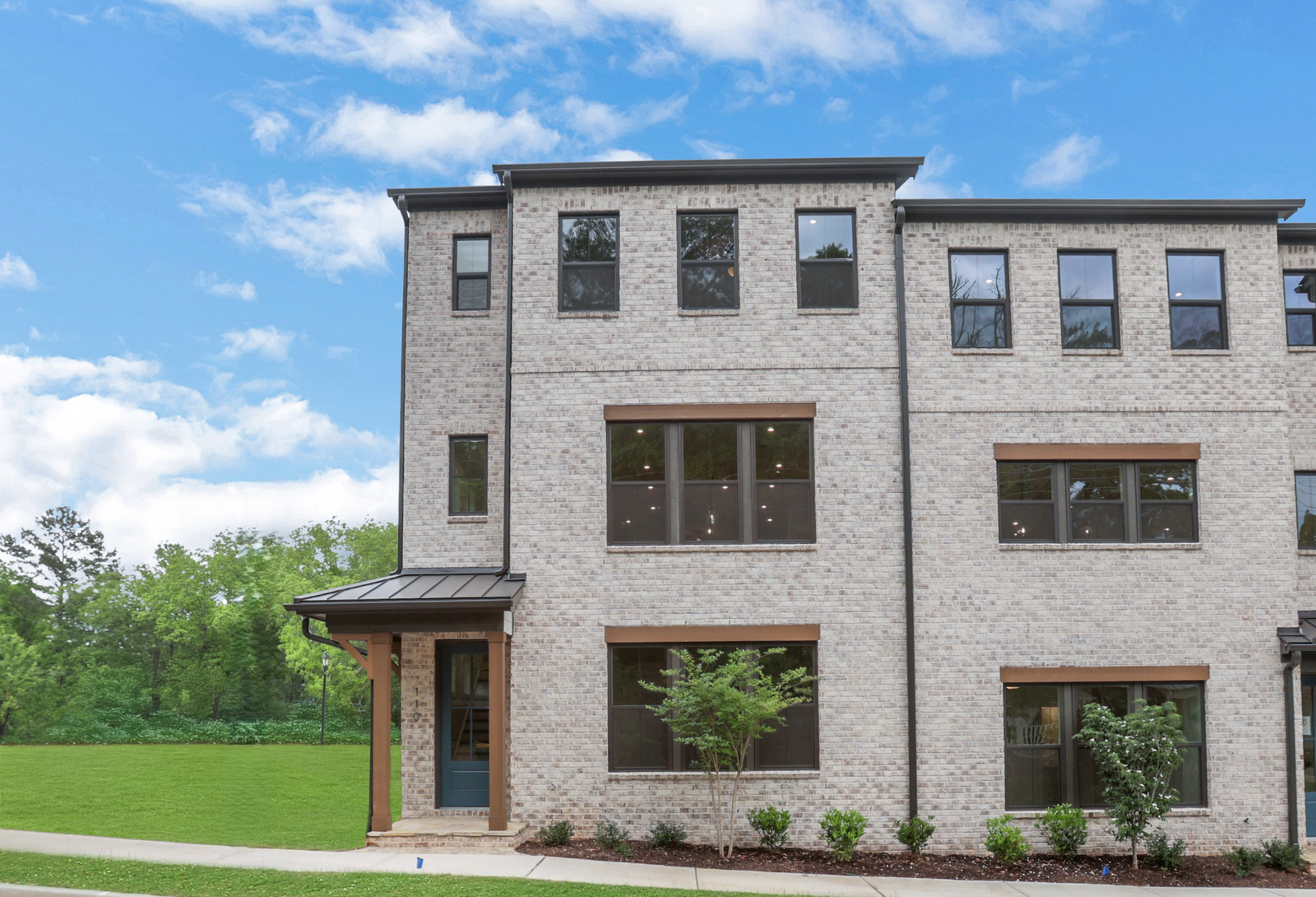 front of 3-story townhome with light brick and wood accents