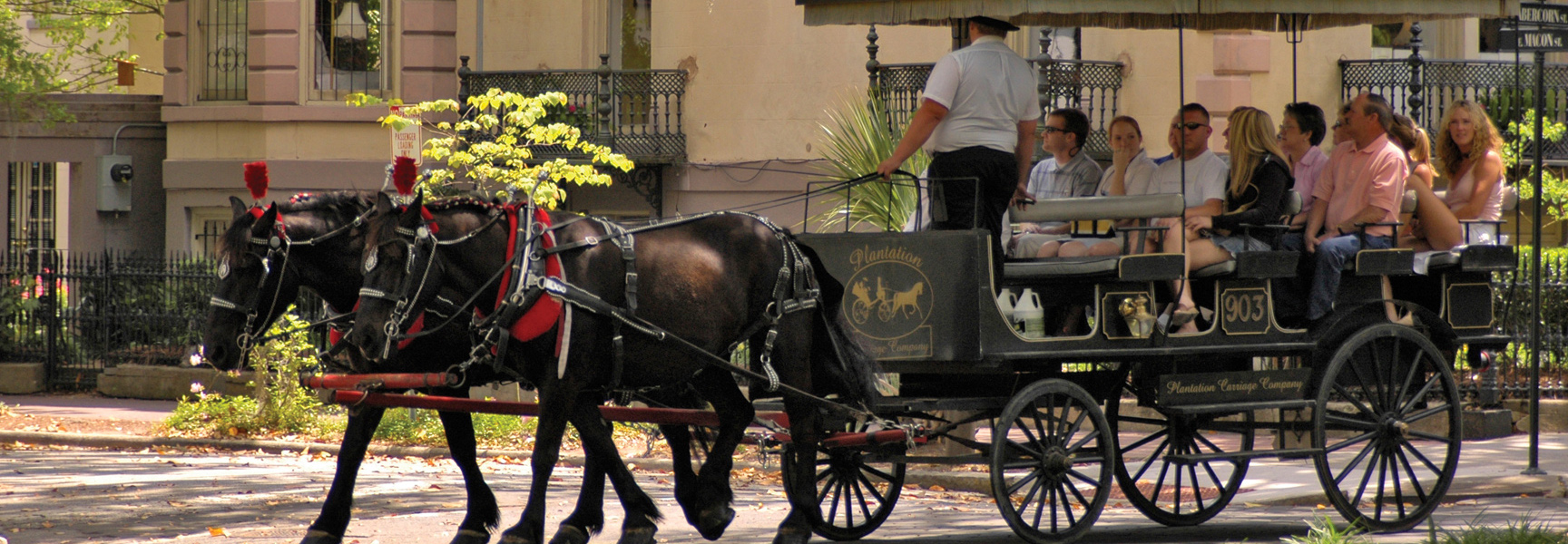 A horse-drawn carriage full of tourists explores the historic streets of Savannah, Georgia.