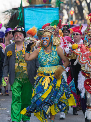 Participants in colorful costumes and ornate masks perform during a grand Mardi Gras parade in New Orleans, Louisiana.