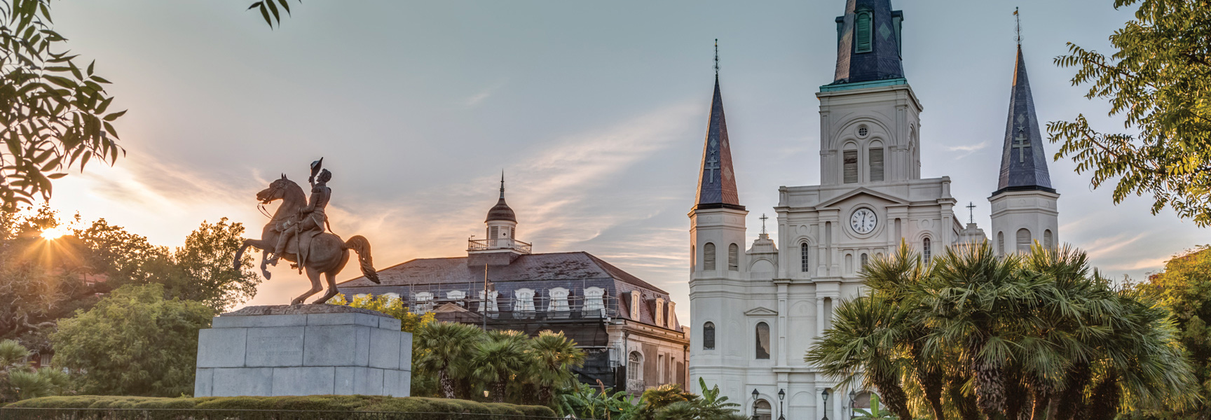 The sun sets behind the Andrew Jackson statue and St. Louis Cathedral in Jackson Square, New Orleans.