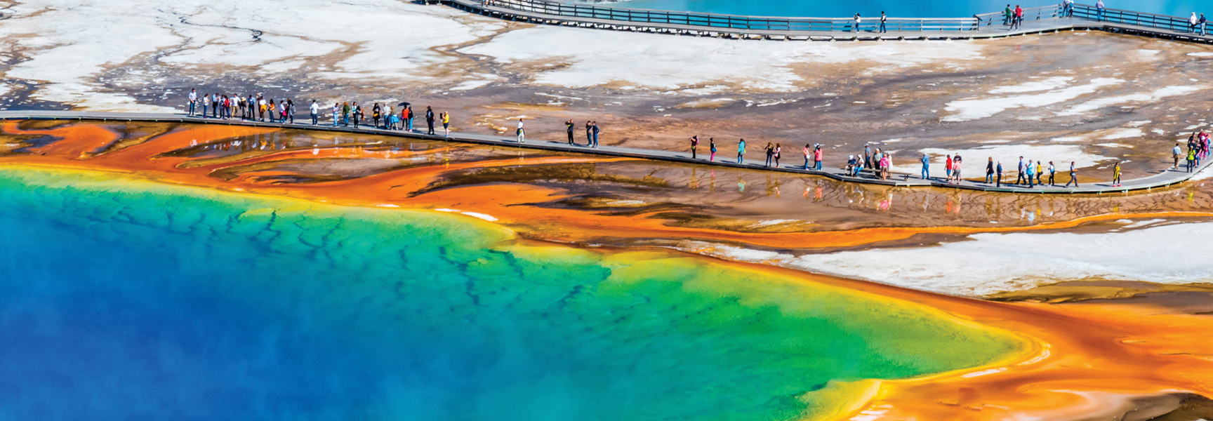 An aerial view of tourists on a boardwalk at the colorful Grand Prismatic Spring in Yellowstone National Park, located in Montana and Wyoming.