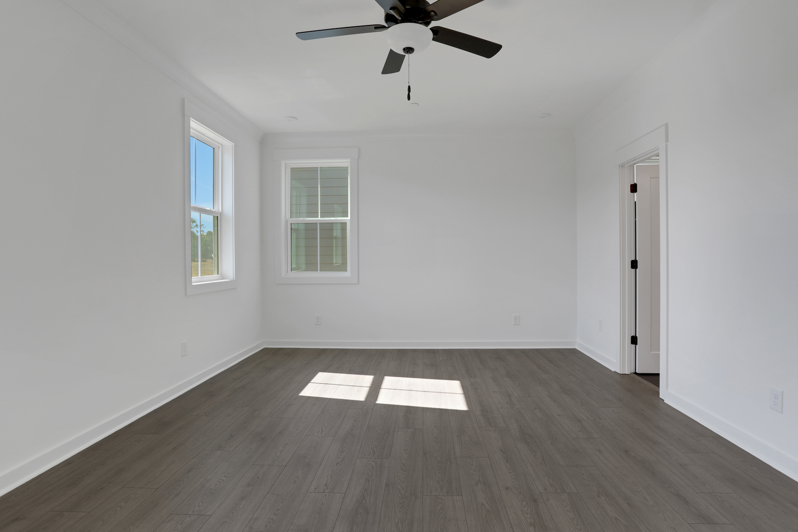 primary bedroom with windows and hard surface flooring