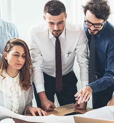 2 men and a women at a desk looking at paperwork