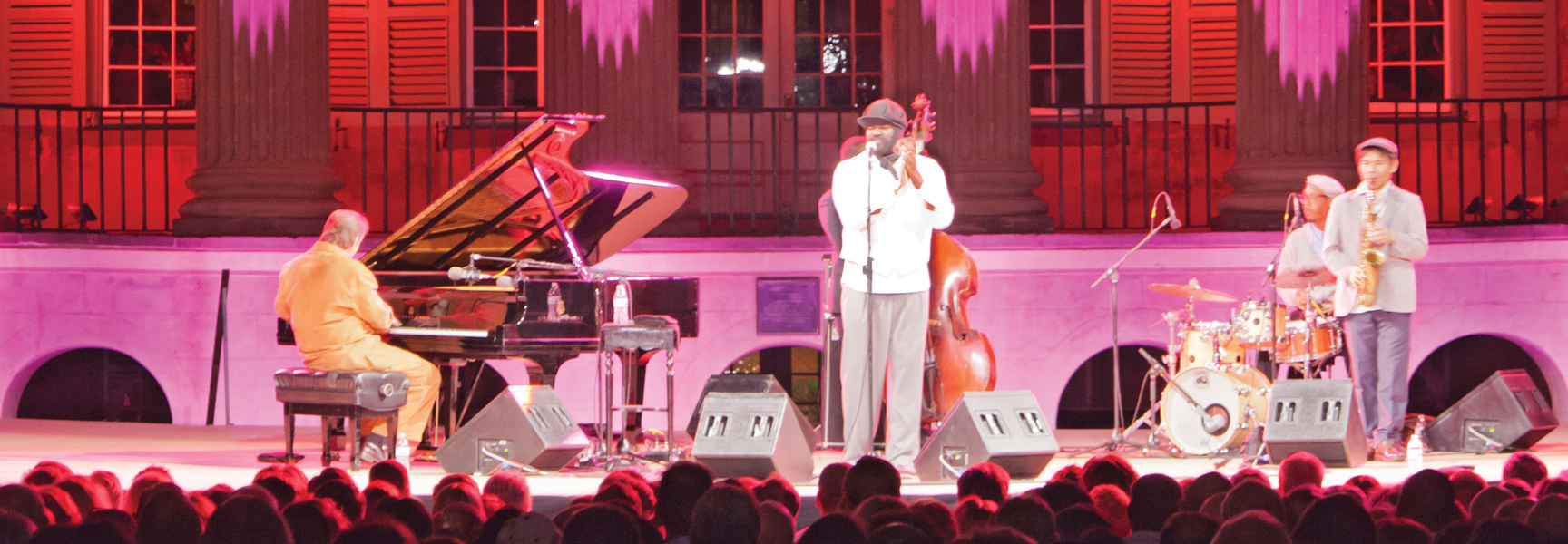 A jazz band performs on an outdoor stage under pink lights at the Spoleto Festival USA in Charleston, South Carolina.