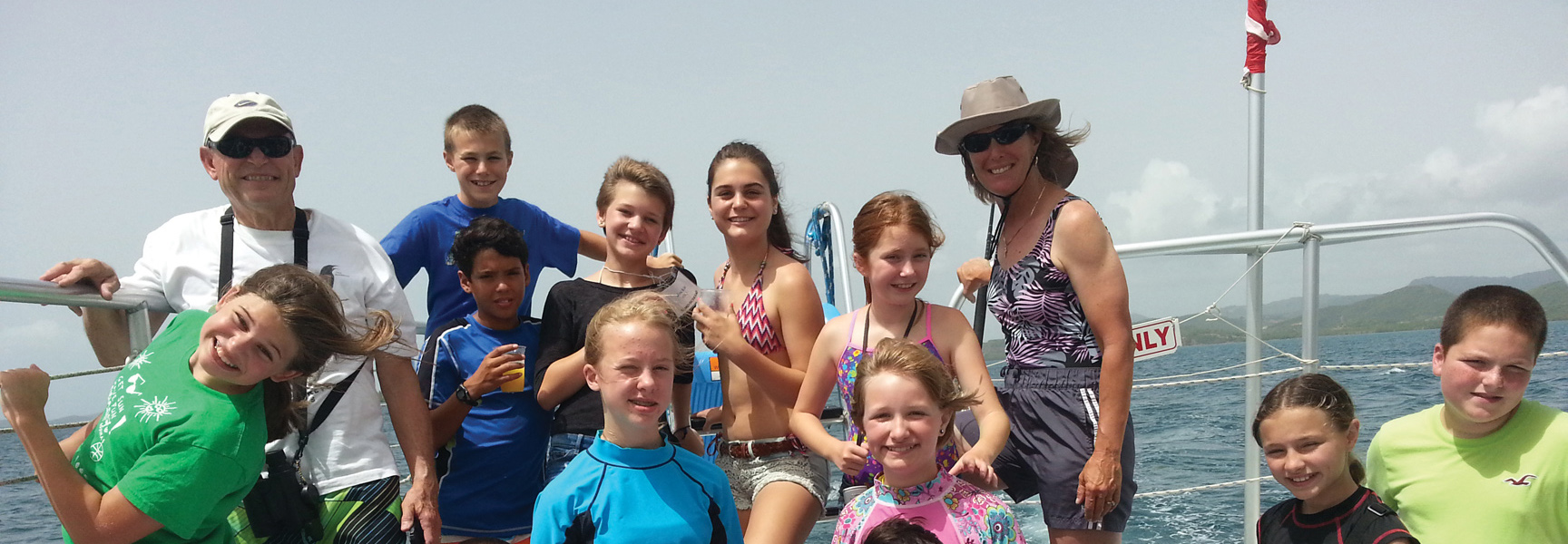 A multi-generational group of adults and children smile for a photo on a boat in Puerto Rico.