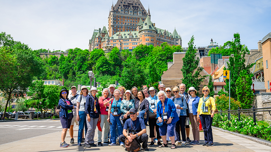 A group of travelers on a walking tour pose for a photo in Old Québec with the historic Château Frontenac in the background.