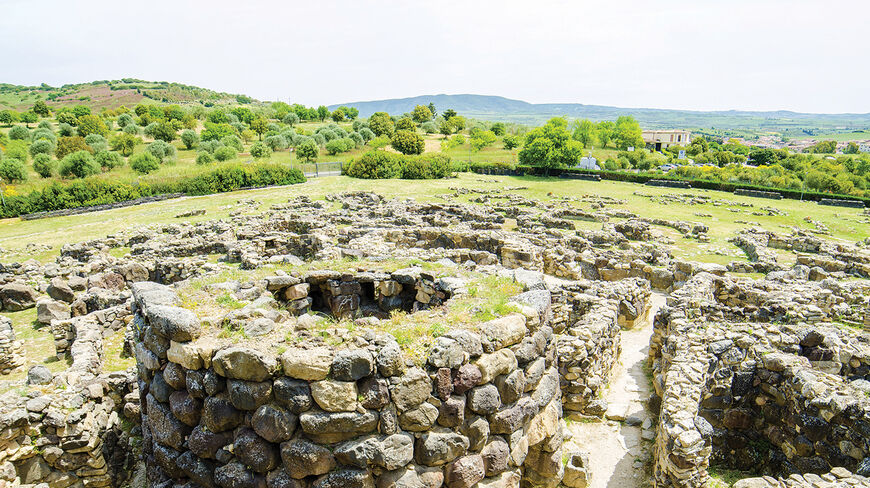 Ancient megaliths and stone ruins of a prehistoric civilization in the sun-soaked landscape of Sardinia, Italy.