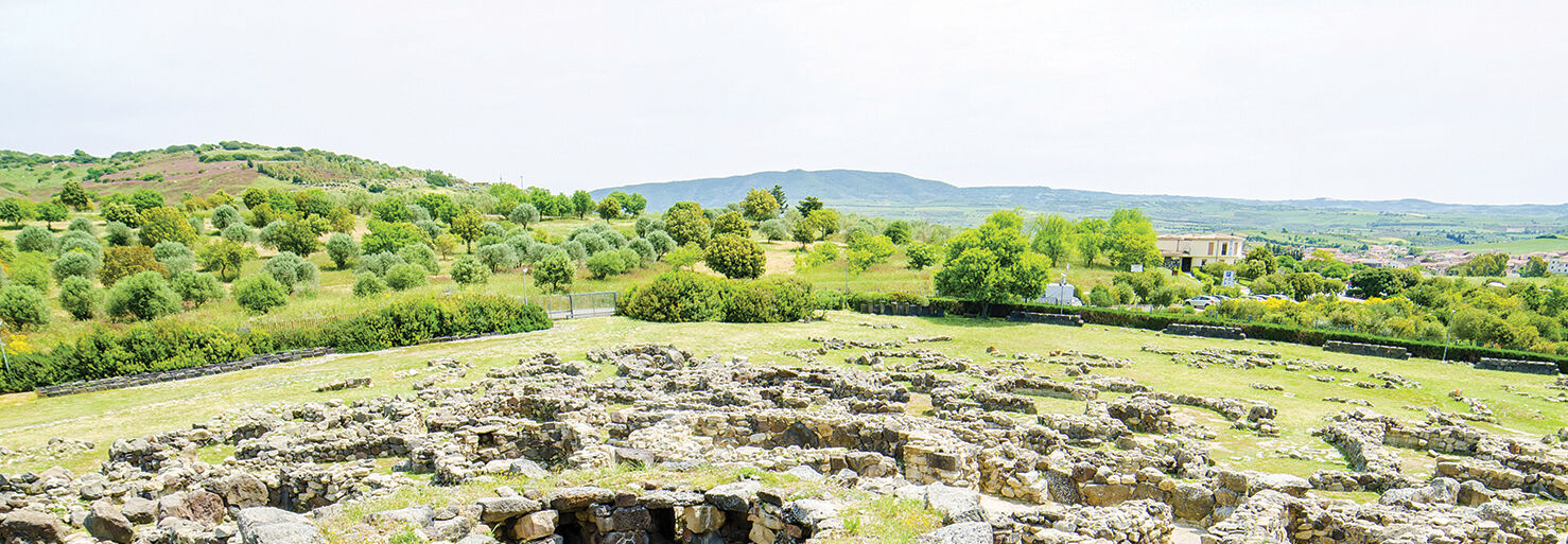 Ancient megaliths and stone ruins of a prehistoric civilization in the sun-soaked landscape of Sardinia, Italy.