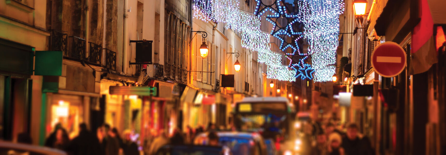 A street in Paris, France, illuminated with star-shaped festive lights and hanging decorations during a New Year's Eve celebration.