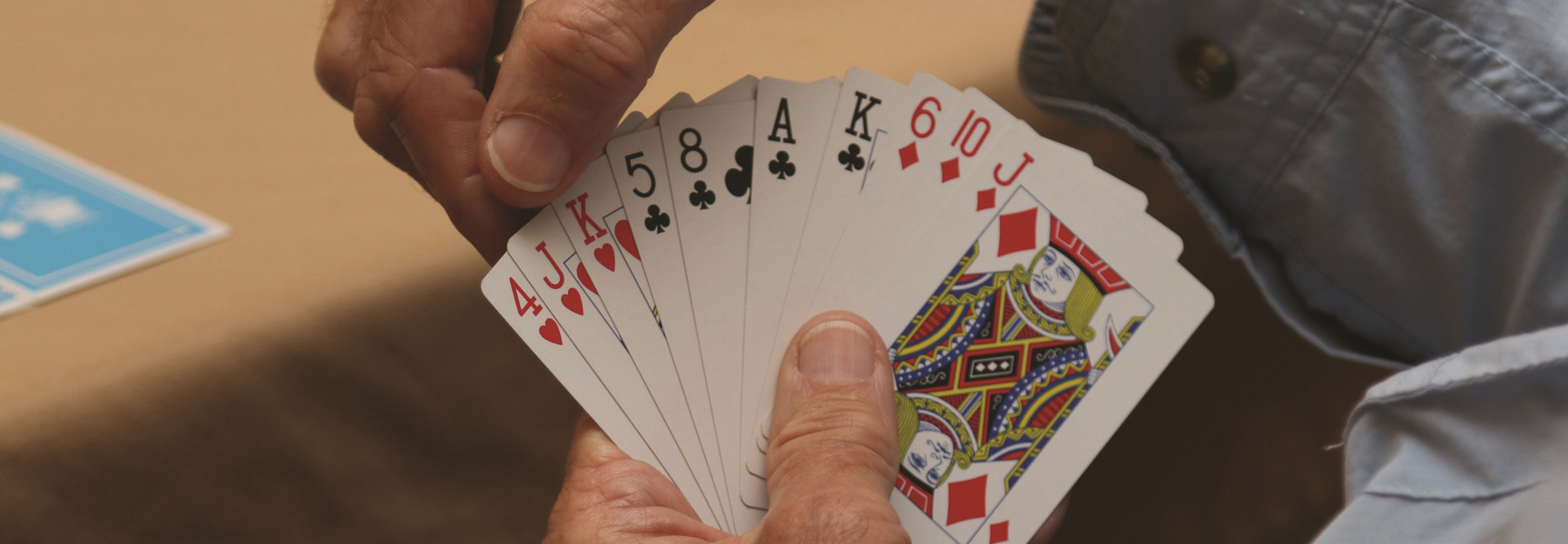 A person's hands carefully arrange a fanned-out hand of playing cards during a bridge game in California.