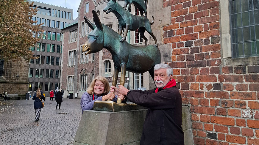 A man and a woman pose with the famous Town Musicians of Bremen bronze statue in Germany.