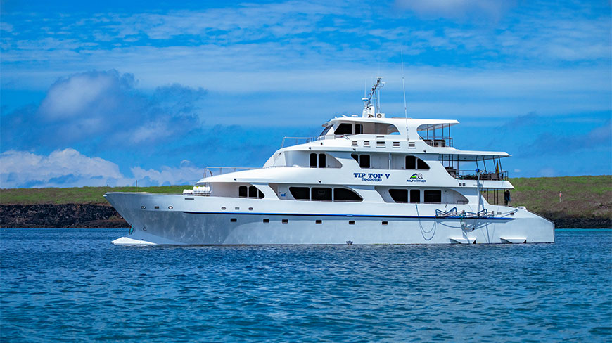 The white yacht Tip Top V floats on the blue waters of Genovesa Island in the Galapagos.