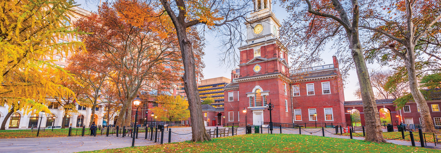 Independence Hall in Philadelphia, Pennsylvania, surrounded by trees with colorful autumn foliage during the day.