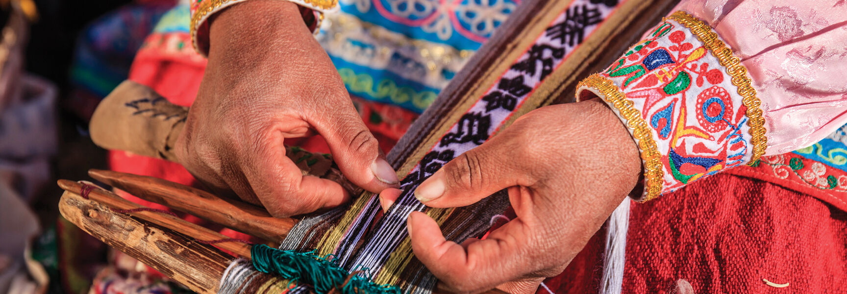 Indigenous Peruvian hands weaving intricate, traditional patterns on a wooden loom, illustrating the enduring cultural heritage of ancient Andean civilization.