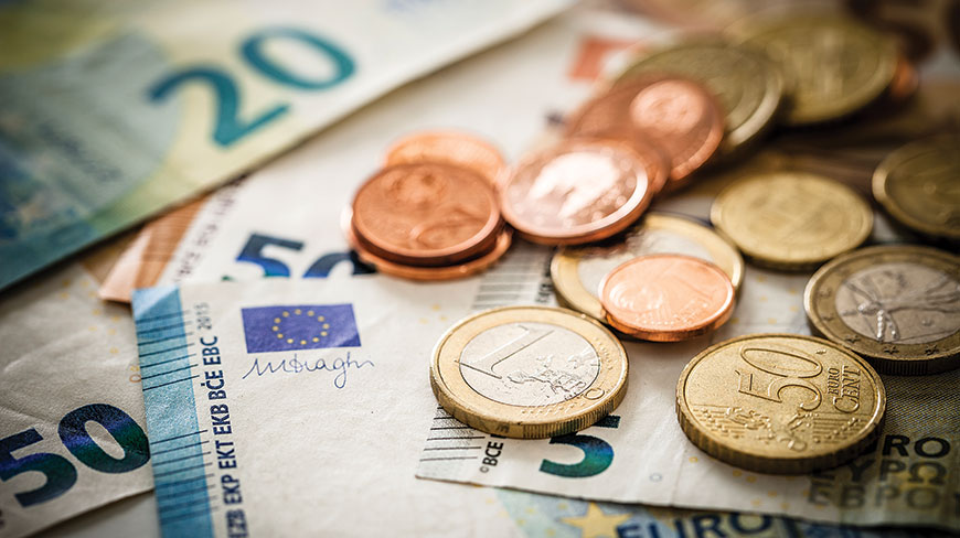A close-up photograph of various euro coins and banknotes, including 50 and 20 euro bills, scattered together.