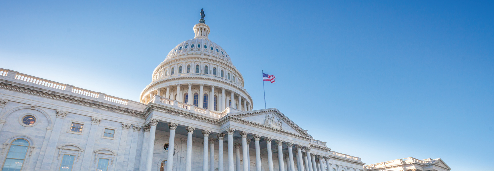 The United States Capitol building in Washington, D.C. against a clear blue sky.