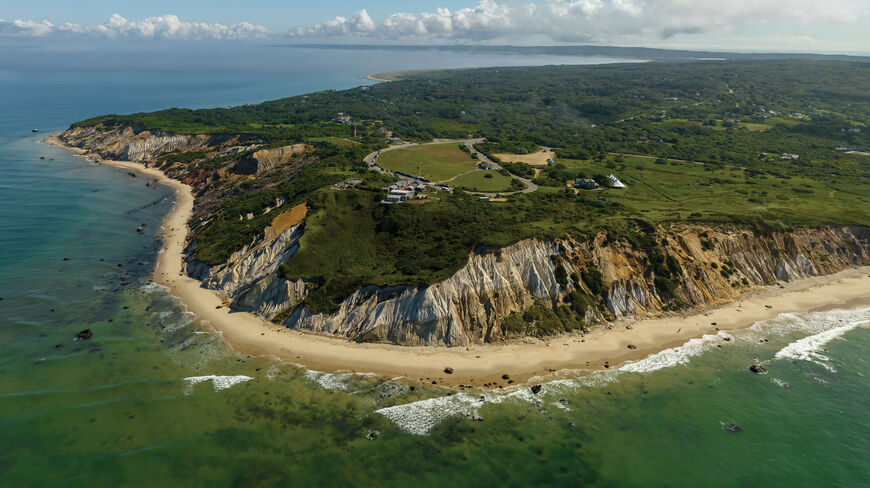 Aerial view of the iconic Gay Head Cliffs on Martha’s Vineyard, featuring colorful clay bluffs, a sandy beach, and clear coastal New England waters.