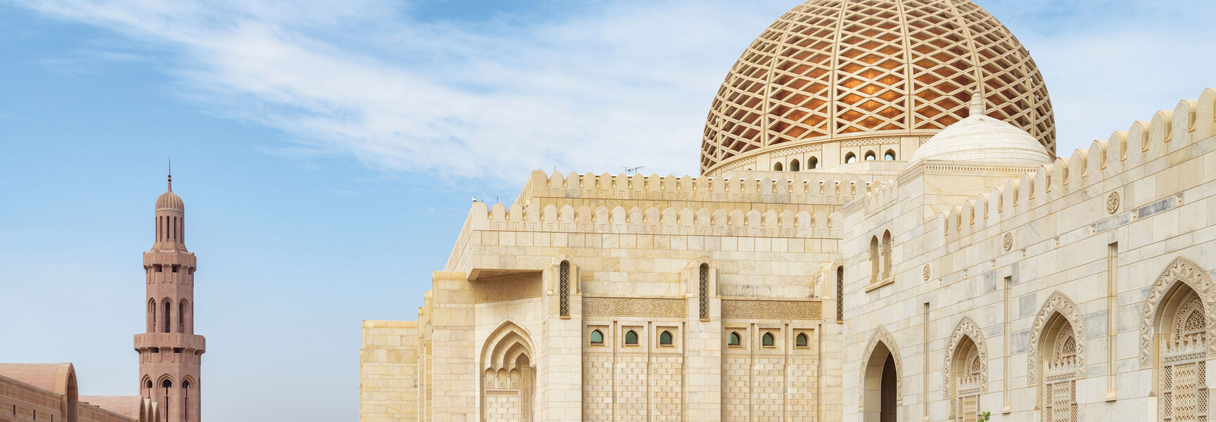 The Sultan Qaboos Grand Mosque in Oman features an ornate golden dome and minaret, showcasing the region's rich Arabian history and heritage.