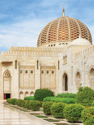 The Sultan Qaboos Grand Mosque in Oman features an ornate golden dome and minaret, showcasing the region's rich Arabian history and heritage.