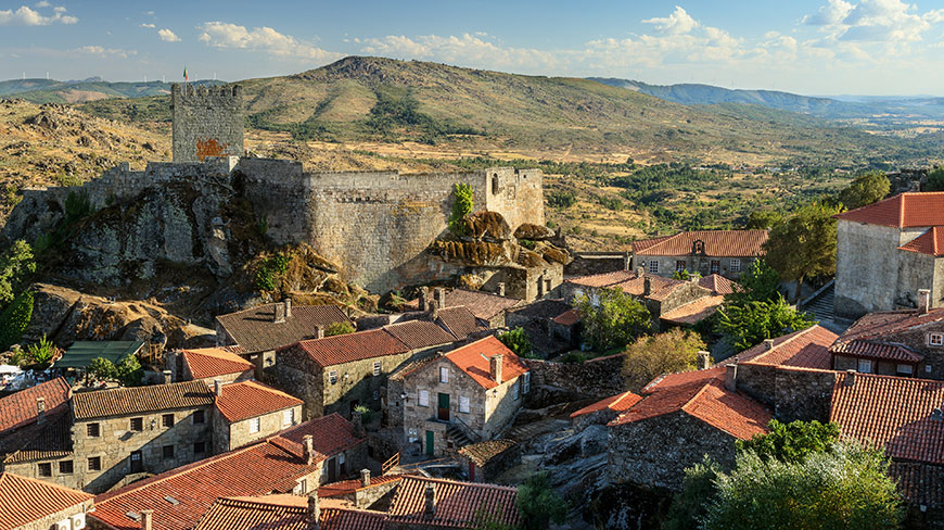 An ancient castle overlooks a village with red-tiled roofs nestled in the hills of Costa Rica.