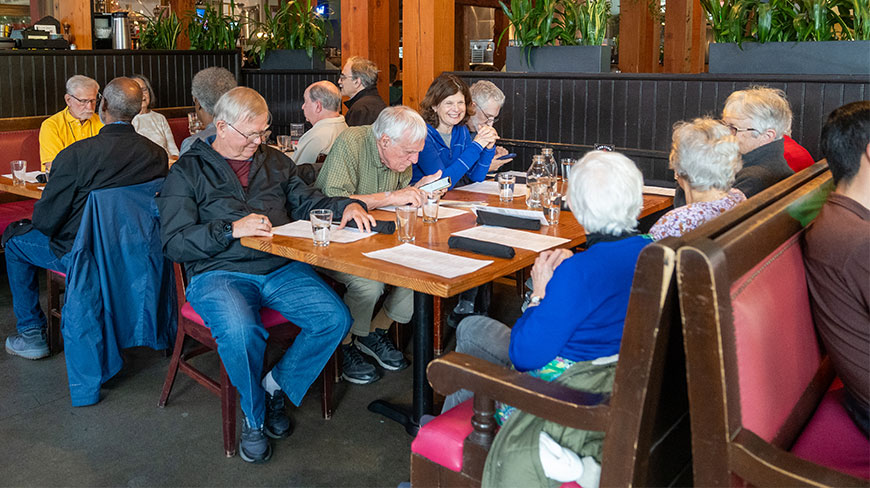 A group of people gather at long wooden tables inside Deschutes Brewery in Portland, Oregon, to look at papers and menus.