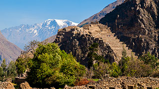 Stone ruins of Ollantaytambo are built into a mountainside in the Sacred Valley, with a snow-capped peak in the distance.