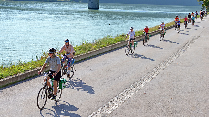 Cyclists ride along a paved path next to the Danube River in Schlögen, Austria.