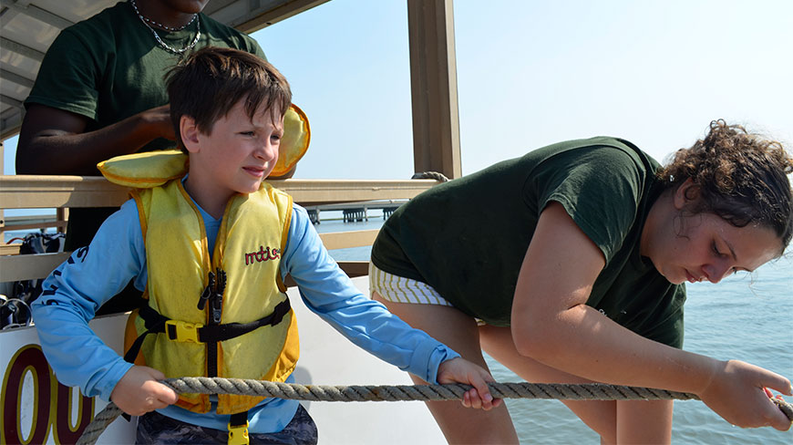A young boy and woman pull a trawl net rope during an ocean science boat ride at Wallops Island, Virginia.